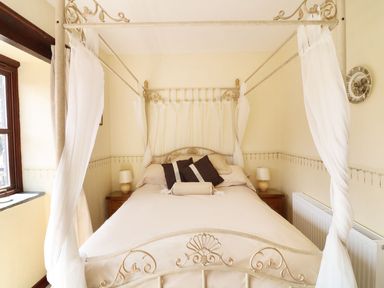 A bedroom with a canopy bed two bedside tables and lamps at The Corn Tallet in Westleigh near Bideford