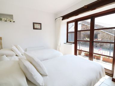 A bedroom with two beds white bedding glass door leading outside at The Corn Tallet in Westleigh near Bideford