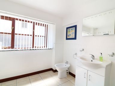 A bathroom with a sink cabinet a bidet a mirror a framed picture and a window with vertical blinds at The Corn Tallet in Westleigh near Bideford
