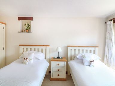 A bedroom with two single beds and a nightstand with a lamp at The Corn Tallet in Westleigh near Bideford
