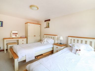 A bedroom with two single beds bedside table with lamp wardrobe and dressing table at The Corn Tallet in Westleigh near Bideford