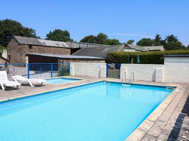 An outdoor swimming pool with two white lounge chairs and a small fenced hot tub at The Corn Tallet in Westleigh near Bideford