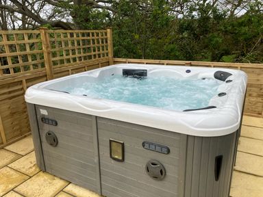 An outdoor hot tub with bubbling water surrounded by wooden privacy fencing at The Corn Tallet in Westleigh near Bideford