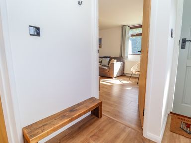 A hallway with a wooden bench and an open door leading to a living room with a sofa and chair at Rollin Dunes in Humberston Lincolnshire