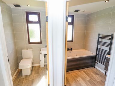 A bathroom with a toilet and a sink and a bathroom with a bathtub and towel rack at Rollin Dunes in Humberston Lincolnshire