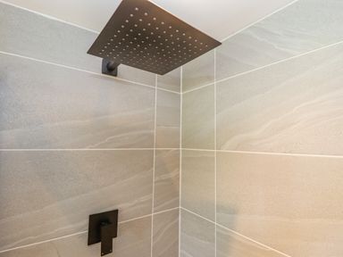 A shower area with a square rainfall showerhead and a control lever on tiled walls at Rollin Dunes in Humberston Lincolnshire