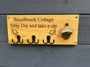 A wooden sign with hooks and a bottle opener at Wood Brook Cottage in Crowan
