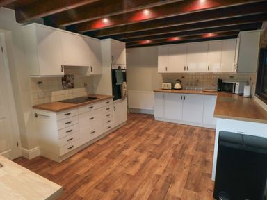 A kitchen with white cabinets wooden countertops and wooden floor at Beaconsfield Cottage in Burniston near Scalby