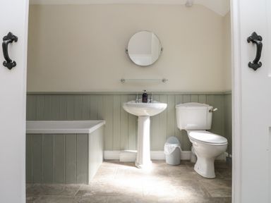 A bathroom with a bathtub sink toilet and a small trash bin at Beaconsfield Cottage Burniston near Scalby
