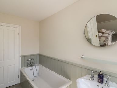 A bathroom with a bathtub sink mirror and soap dispenser at Beaconsfield Cottage in Burniston near Scalby
