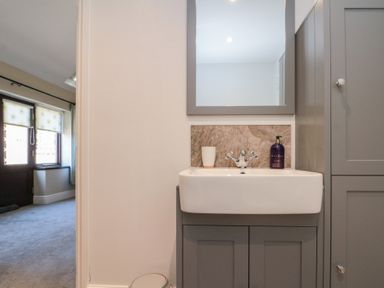 A bathroom sink with grey cabinetry and a mirror above at Beaconsfield Cottage in Burniston near Scalby