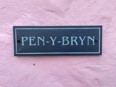 A black and white house name sign reading PEN-Y-BRYN on a pink textured wall at Pen- y- Bryn @ Canllefaes in Penparc near Cardigan