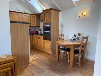 A kitchen with wooden cabinets and a dining table with two chairs at Pen- y- Bryn @ Canllefaes Penparc near Cardigan