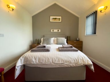 A bedroom with a double bed with folded towels bedside tables and wall lamps at Pen- y- Bryn @ Canllefaes in Penparc near Cardigan