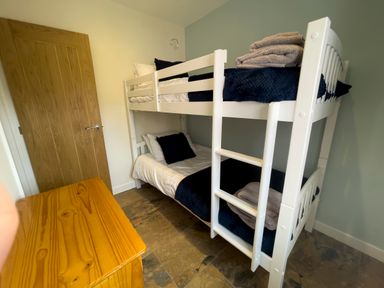 A bedroom with a white bunk bed with blue bedding and a wooden chest at The Byre @ Canllefaes in Penparc near Cardigan