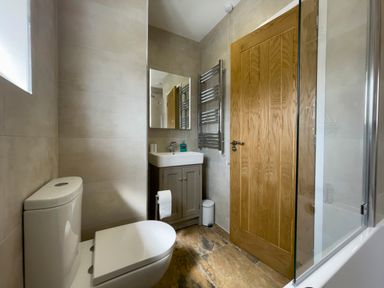 A bathroom with a toilet sink mirror wooden door and a glass shower screen at The Byre @ Canllefaes in Penparc near Cardigan