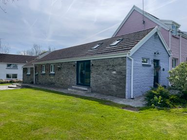 A stone and pastel blue painted house with skylights and lawn in the front at The Byre @ Canllefaes Penparc near Cardigan
