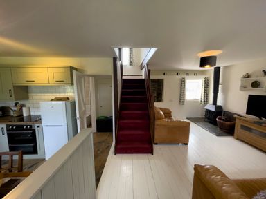 A living room with a staircase between kitchen and seating area at The Shippen @ Canllefaes in Penparc near Cardigan