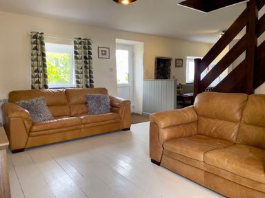 A living room with two brown leather sofas near a staircase and a door at The Shippen @ Canllefaes in Penparc near Cardigan