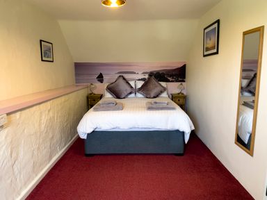 A bedroom with a double bed pillows towels bedside tables lamps and a wall mirror at The Shippen @ Canllefaes Penparc near Cardigan