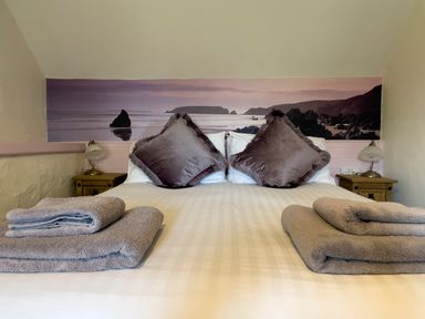 A bed with two large pillows and folded towels on each side with bedside tables and lamps at The Shippen @ Canllefaes in Penparc near Cardigan