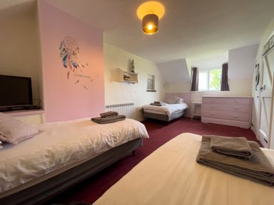 A bedroom with three single beds a pink dresser and a window with curtains at The Shippen @ Canllefaes Penparc near Cardigan