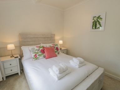 A bedroom with a double bed two bedside tables with lamps and a framed picture on the wall at Bwthyn Pengwern in Saron near Caernarfon