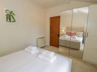 A bedroom with a bed white towels on the bed a wooden door and a wardrobe with mirrored doors at Bwthyn Pengwern in Saron near Caernarfon