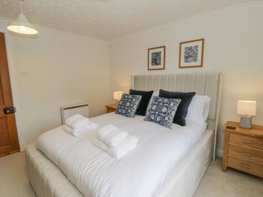 A bedroom with a bed with pillows and folded towels bedside tables with lamps and framed pictures on the wall at Bwthyn Pengwern in Saron near Caernarfon