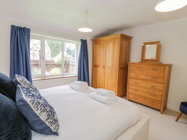 A bedroom with a bed pillows towels wooden wardrobe chest of drawers and blue curtains at Bwthyn Pengwern in Saron near Caernarfon