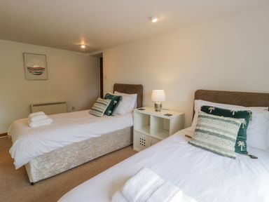 A bedroom with two single beds with white bedding and patterned pillows at Bwthyn Pengwern in Saron near Caernarfon