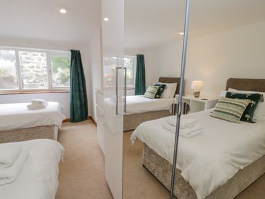 A bedroom with two single beds each with pillows and towels and a bedside table with a lamp at Bwthyn Pengwern in Saron near Caernarfon