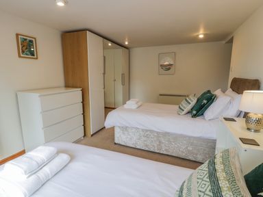 A bedroom with two beds dresser wardrobe and lamp at Bwthyn Pengwern in Saron near Caernarfon