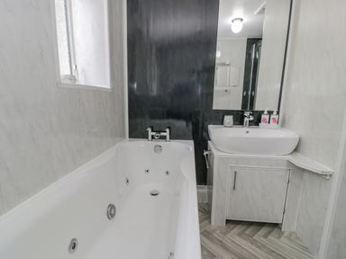 A bathroom with a bathtub and a sink with a mirror at Bwthyn Pengwern in Saron near Caernarfon