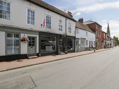 A street view of white and red brick buildings with shops and houses and a church spire in the background at Cuckoo Cottage in Upton Upon Severn
