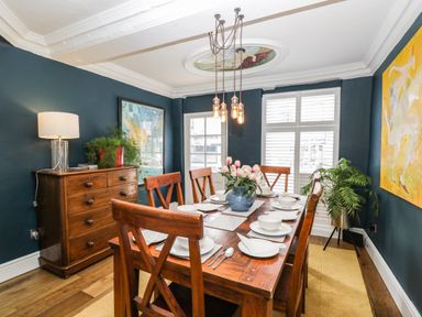 A dining room with a wooden table set for six and dark blue walls at Cuckoo Cottage in Upton Upon Severn