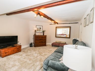 A living room with a sofa chest of drawers a television and a large wall mirror at Cuckoo Cottage in Upton Upon Severn