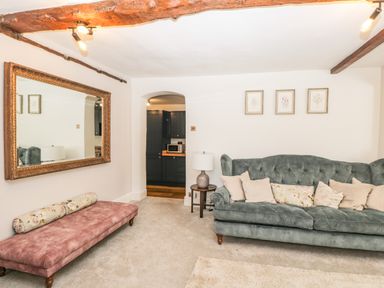 A living room with a green sofa and a pink bench under a large mirror at Cuckoo Cottage in Upton Upon Severn