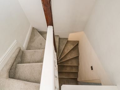 A carpeted staircase with a wooden handrail and white walls at Cuckoo Cottage in Upton Upon Severn