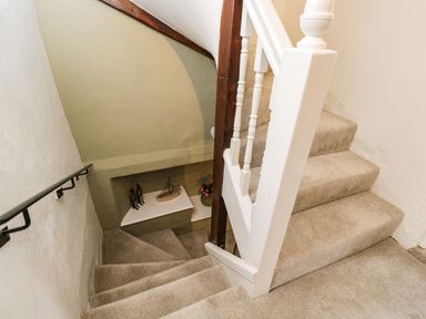A carpeted staircase with white banister and decorative items on a wall shelf at Cuckoo Cottage in Upton Upon Severn