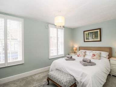 A bedroom with a double bed two bedside tables two windows and a framed picture at Cuckoo Cottage in Upton Upon Severn
