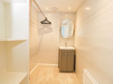 A small room with a vanity sink and mirror a radiator and open shelves at Cuckoo Cottage in Upton Upon Severn