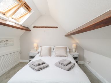A bedroom with a bed with pillows and towels two bedside tables with lamps and a skylight window at Cuckoo Cottage in Upton Upon Severn