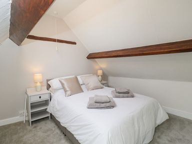 A bedroom with a double bed white bedding two bedside tables with lamps and exposed wooden beams at Cuckoo Cottage in Upton Upon Severn