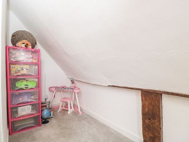 A corner of a room with a pink plastic drawer unit and a pink children's keyboard with stool at Cuckoo Cottage in Upton Upon Severn