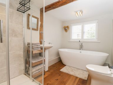 A bathroom with a bathtub a pedestal sink a shower cubicle and a toilet at Cuckoo Cottage in Upton Upon Severn