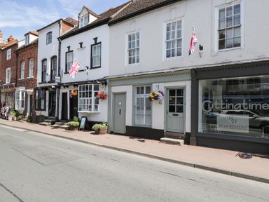 A street view of buildings with shops and hanging flower baskets and union jack flags at Cuckoo Cottage in Upton Upon Severn