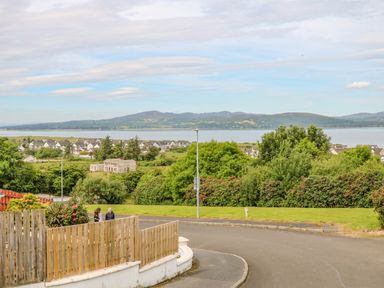 A street with wooden fences and greenery overlooking houses water and distant hills at 12 Hillview Ludden near Buncrana