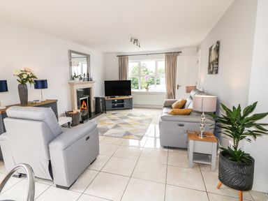 A living room with grey sofas a television a fireplace and a plant at 12 Hillview Ludden near Buncrana