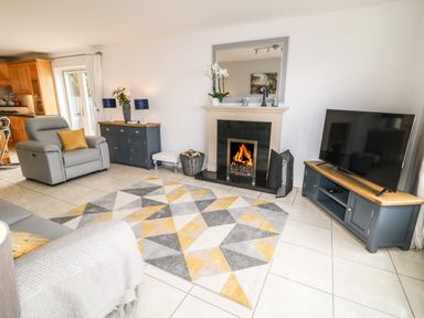 A living room with a fireplace a television a gray chair and geometric rug at 12 Hillview in Ludden near Buncrana
